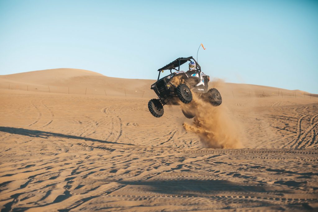 Man jumping in the air with ATV in a sand desert